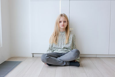 Portrait of young woman sitting on hardwood floor at home