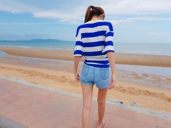 Rear view of young woman standing at beach