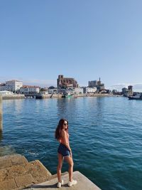 Woman standing by sea against clear blue sky