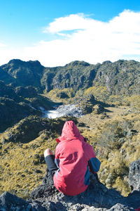 Rear view of woman standing on mountain against sky