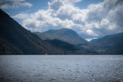 Scenic view of lake by mountains against sky