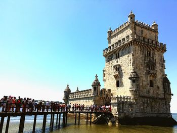 Tourists waiting in line on jetty leading to historic structure