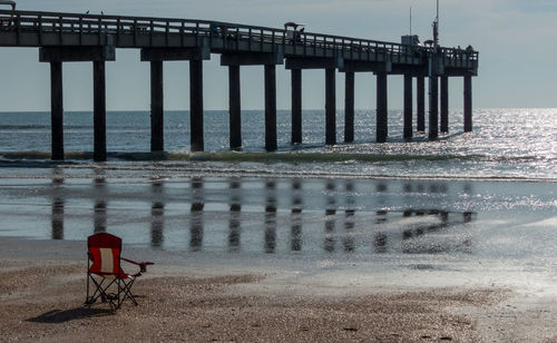 Rear view of pier on beach against sky