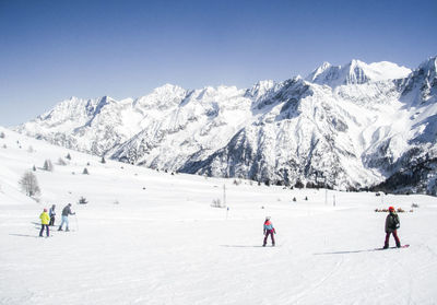 People skiing by snowcapped mountain against sky