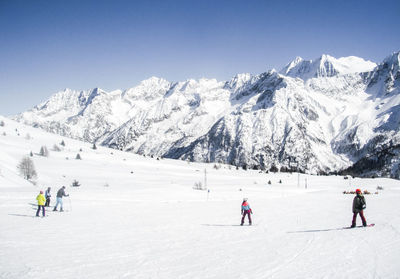 People skiing on snowcapped mountain against clear sky