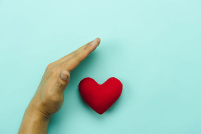 Close-up of hand holding heart shape over white background