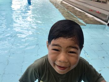 Close-up portrait of smiling boy against swimming pool