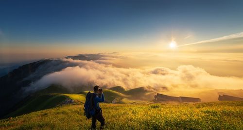 High angle view of man standing on mountain against sky during sunset