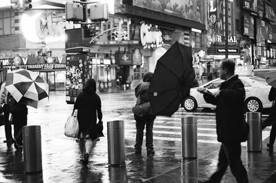 Rear view of people walking on wet street