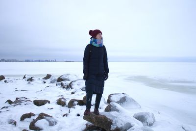 Man standing on snow covered land against sea