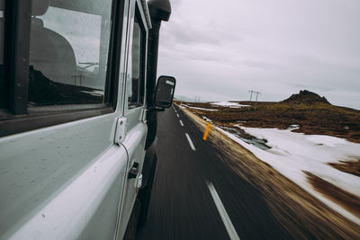 Car moving on road against sky seen through glass window