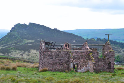 Old ruin on field by mountain against sky