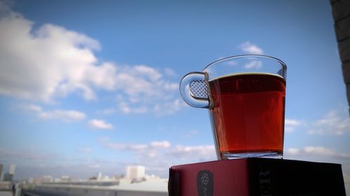 Close-up of herbal tea in glass cup against sky