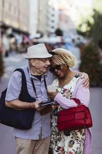 Senior man embracing woman while standing on street in city