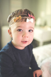 Portrait of baby boy wearing headbands while sitting on bed at home