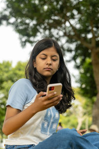 Young woman using mobile phone while sitting outdoors