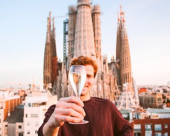 Man holding up a glass of champagne in front of sagrada familia