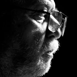 Close-up of thoughtful senior man against black background