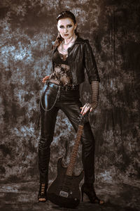 Portrait of young woman standing against wall