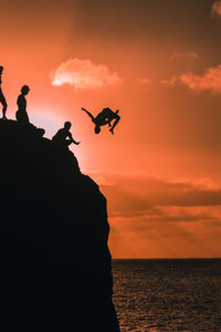Silhouette bird flying over sea against sky during sunset