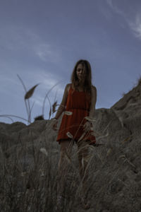 Woman with arms raised on field against sky