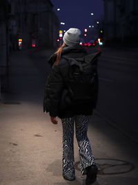 Rear view of woman walking on street at night