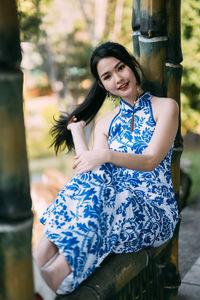 Portrait of young woman sitting on railing