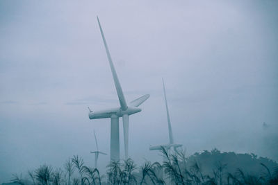 Wind turbines on field against sky