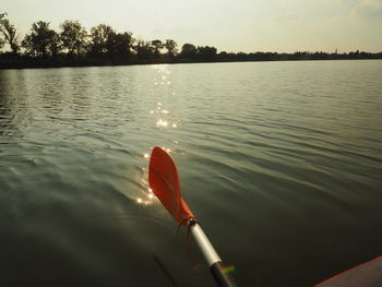 Cropped image of oar over river against sky