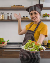 Portrait of smiling young man holding food in kitchen