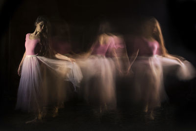 Woman standing on illuminated lighting equipment against black background