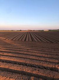 Scenic view of geometric plowed agricultural field against clear sky
