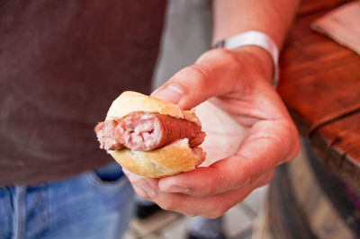 Midsection of man holding hot dog