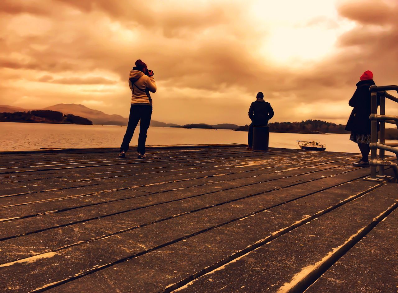 sky, sunset, cloud - sky, water, cloudy, sea, full length, lifestyles, scenics, tranquility, cloud, leisure activity, tranquil scene, beauty in nature, standing, weather, nature, beach