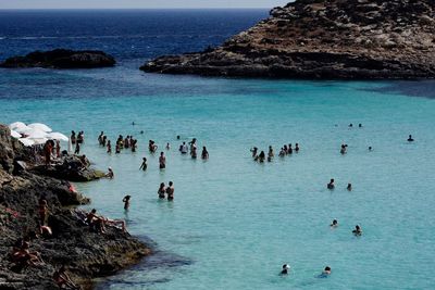 People swimming in sea against blue sky