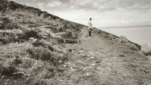 Rear view of woman walking on landscape against sky