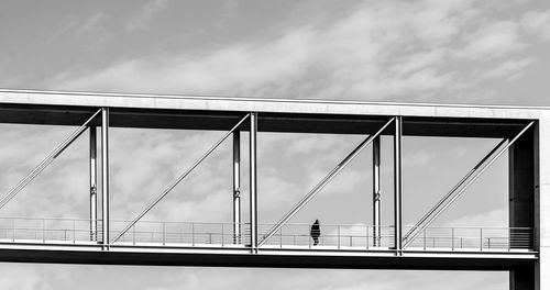 Low angle view of man walking on bridge against sky