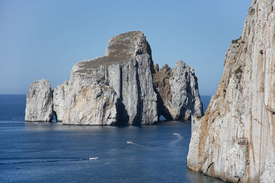 Scenic view of sea and rocks against clear blue sky