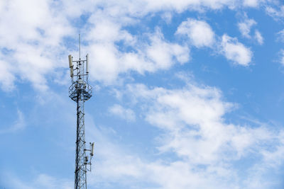 Low angle view of communications tower against cloudy sky