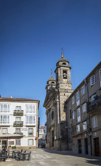 Street amidst buildings against clear blue sky