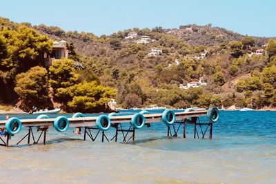 Chairs and table by swimming pool against clear blue sky