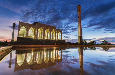 Illuminated historical building reflecting in pool during sunset