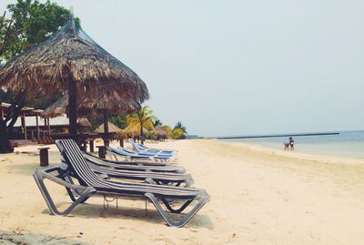 Chairs on beach against clear sky