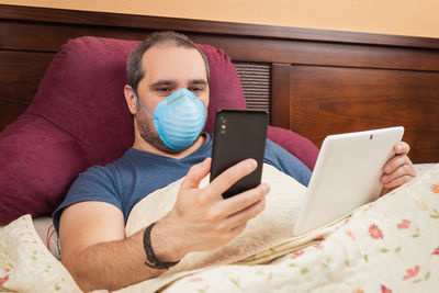 Midsection of man using mobile phone on bed