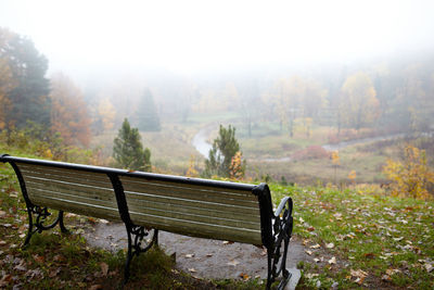 Empty park bench during foggy weather