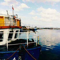 Boats moored at harbor against sky