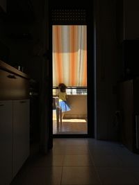 Rear view of woman standing by door at home