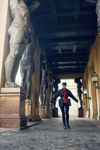 Fashionable woman in jacket, sunglasses, red shirt stands. sculpture atlanteans in saint petersburg