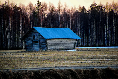 Barn on field against trees in forest