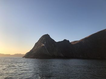 Scenic view of sea and mountains against clear sky